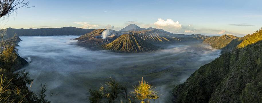 View of a sea of fog blankets the valley floor, partially obscuring the base of the majestic, rugged volcanic peaks, Bromo, East Java, Indonesia.