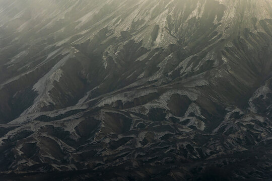 View of rugged, shadowy mountains rise in a dramatic landscape under a soft, muted sky, creating a sense of awe and solitude, Bromo, East Java, Indonesia.