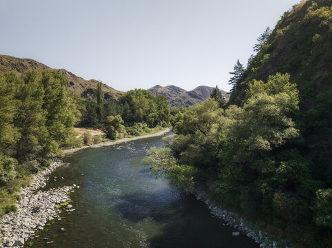 Aerial view of the Mtkvari River winding through forested hills, the water reflecting the sky's soft light, a tranquil scene of nature's embrace, Samtskhe-Javakheti, Georgia.