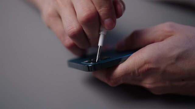 Close-up of male hand cleaning smartphone camera lens with dedicated brush pen, performing routine device maintenance for optimal clarity and improving mobile photography quality, slow motion.