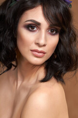 Obraz premium Studio portrait for a beauty advertising campaign. The photo shows a young woman with dark hair. She's barely wearing makeup, her lips are shiny, and her eyes express confidence and calm.