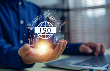 Naklejka premium Businessman holding glowing ISO certification icon with document and checklist graphics, symbolizing quality management, standardization, compliance, and corporate assurance.