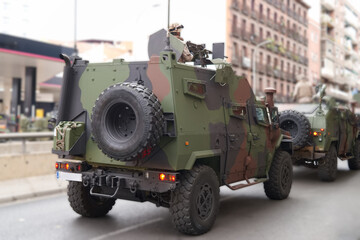 Military vehicles maneuvering on city street in urban setting during daylight