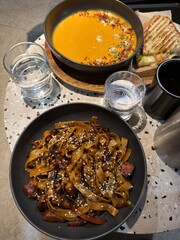 Asian Noodles with Vegetables and Pumpkin Soup on Cafe Table