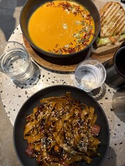 Asian Noodles with Vegetables and Pumpkin Soup on Cafe Table