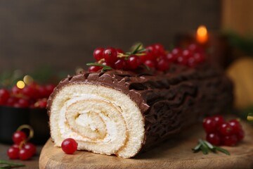 Delicious Yule log (traditional Christmas cake) with redcurrant on wooden table, closeup