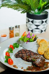 Delicious steak on a plate with salad, garlic bread, and tomatoes. A culinary delight served in a sophisticated setting