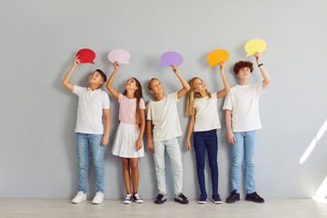 Young teenager school kids in casual clothes holding multicolor paper clouds isolated on gray wall background. Children with empty blank speech bubble for thoughts standing in a row. Idea concept.