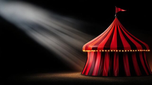 Red-and-white striped circus tent at night with string lights around its base and a spotlight slicing through the darkness.