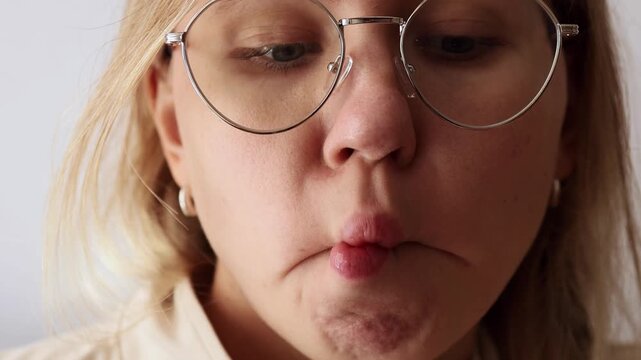Girl in glasses pressing lips comically, showing funny expression of anticipation.