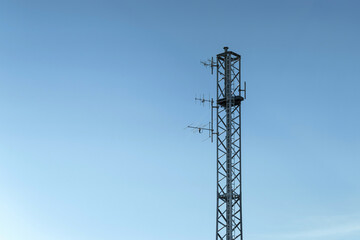 Telecommunication tower stands tall against a clear blue sky during daytime in an urban area
