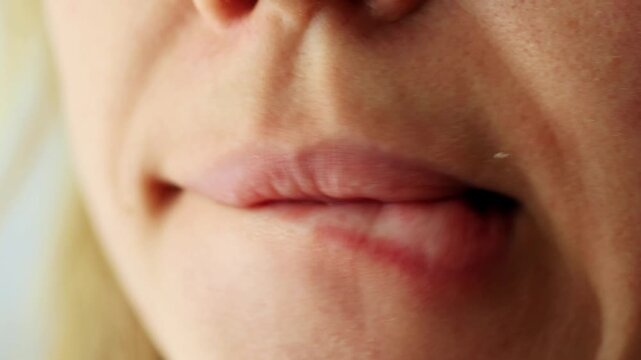 Close-up of female mouth nervously biting her lip, showing tension.