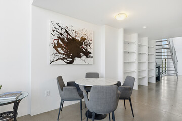 White and black abstract painting hangs on the wall above a dining table