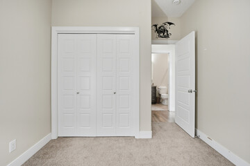 White bedroom with a white closet and a toilet