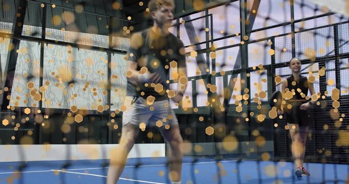 Male padel player adjusting grip executing volley while partner returning ball for fitness
