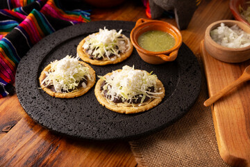 Sopes. Mexican typical food prepared with flattened fried corn dough covered with refried beans, green or red sauce, lettuce, cheese, onion and sour cream. Mexican antojitos.