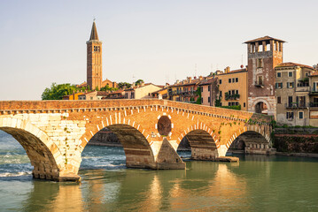 Die römische Ponte Pietra über dem Fluß Etsch in der Altstadt von Verona leuchtet in der Abendsonne, Venetien, Italien