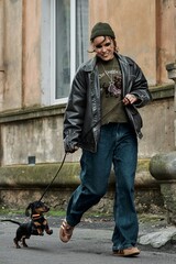 Woman walking a dachshund dog on a leash down a city street