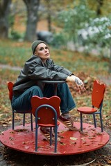 Woman in leather jacket sitting on a vintage merry-go-round in a park