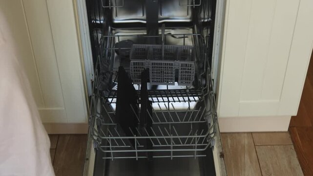 Organizing a dishwasher by carefully placing dirty plates and utensils into the rack. Following a simple process for effective cleaning in the kitchen. A helpful household task demonstrated.