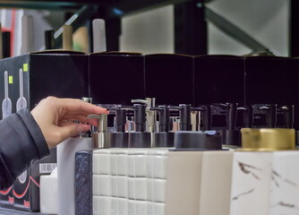 A person's hand selects a modern soap dispenser from a retail store display
