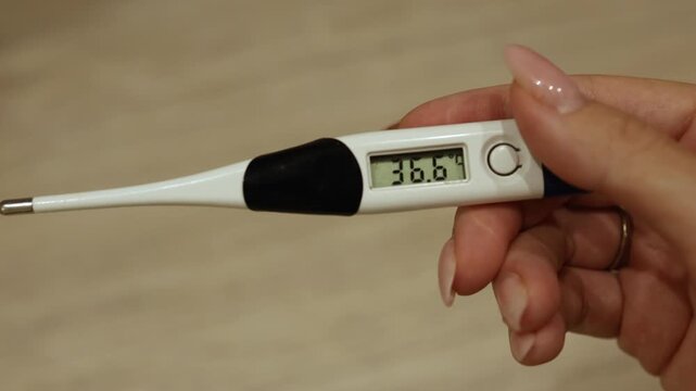 A person uses a digital thermometer to monitor body temperature. Different readings are shown, highlighting how to check for fever and ensure health safety.