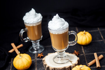 Warm pumpkin spice latte with whipped cream and cinnamon sticks in cozy autumn setting