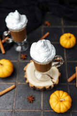 Warm autumnal drink with whipped cream and spices, surrounded by small pumpkins
