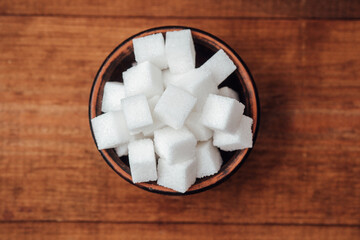 Sugar cubes arranged neatly in a wooden bowl on a rustic wooden table