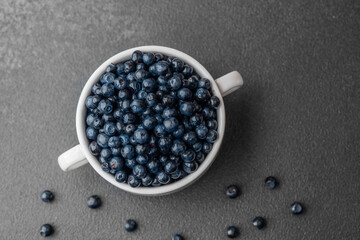 Blueberries with scattered berries on grey for healthy snack or food styling concept
