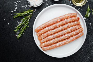 Fresh pork sausages on white plate with herbs and seasonings