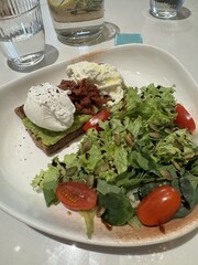 Delicious dish with tomato and greens with toast with egg on a restaurant table
