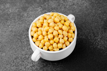 Chickpeas in white bowl on dark background for vegan protein, legume food or healthy eating concept