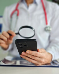 Medical professional examining a smartphone with a magnifying glass