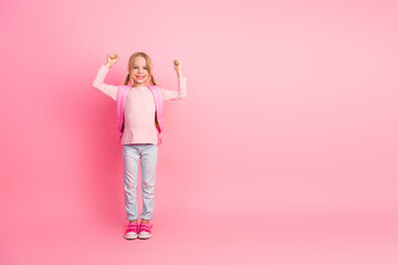 Adorable smiling young girl in pink outfit posing on solid pastel pink background showing cheerful personality and strength