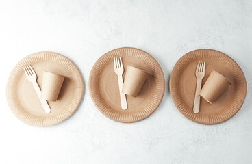 Minimalist arrangement of paper cups and forks on plates over white stone background