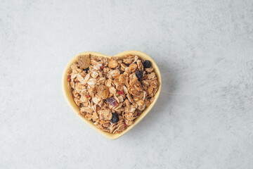 Heart shaped bowl with granola mix on light background