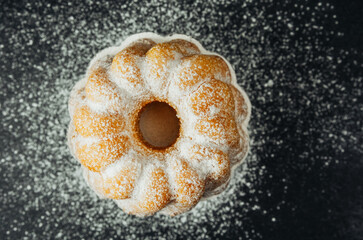 Bundt cake with powdered sugar on black background