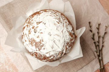 Traditional Easter cake with powdered sugar on soft beige linen background. Rustic homemade dessert for spring holiday