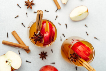 Warm apple cider in glasses with cinnamon sticks, star anise, cloves, and apple slices © reddish