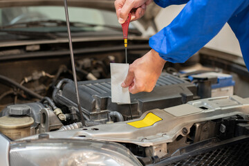Close up of a car mechanic checking oil level in a mechanical at workshop