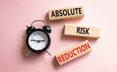 Absolute Risk Reduction symbol. Concept words Absolute Risk Reduction on wooden blocks. Beautiful pink background with alarm clock. Business and Absolute Risk Reduction concept. Copy space.