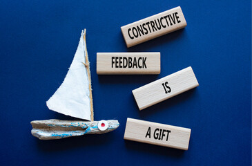 Feedback symbol. Wooden blocks with words Constructive Feedback is a gift. Beautiful deep blue background with boat. Business and Constructive Feedback is a gift concept. Copy space.