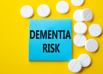 Dementia Risk symbol. Concept word Dementia Risk on blue note. Beautiful yellow background with pills. Medicine and Dementia Risk concept. Copy space