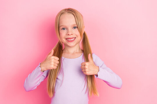 Cute smiling little girl showing thumbs up gesture against pink background, cheerful and adorable young child model - Powered by Adobe