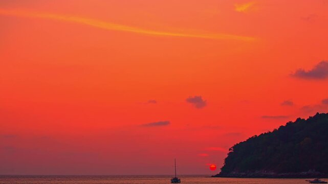 Time lapse A golden tropical sunset paints the sky with vibrant hues, casting shimmering reflections across the calm ocean waves. Picturesque Tropical Sky at Sunset at Kala island Layan beach Phuket