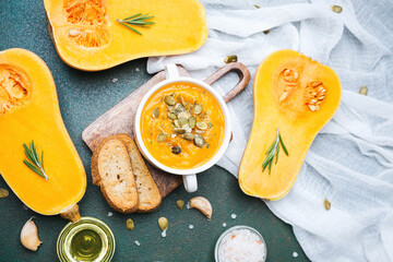 Butternut squash soup with seeds and fresh rosemary on a dark table