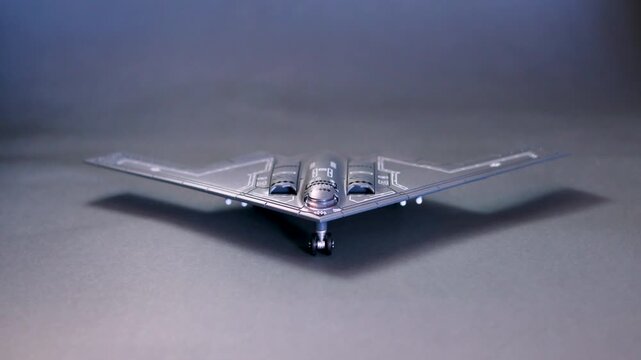 Top view of B2 spirit stealth bomber scale model displayed on a blue surface with five missiles arranged below. The iconic flying wing design represents modern aviation, stealth technology