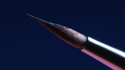 Close-up of a paintbrush with a pointed tip. the brush is black and silver in color and has a shiny, metallic finish.