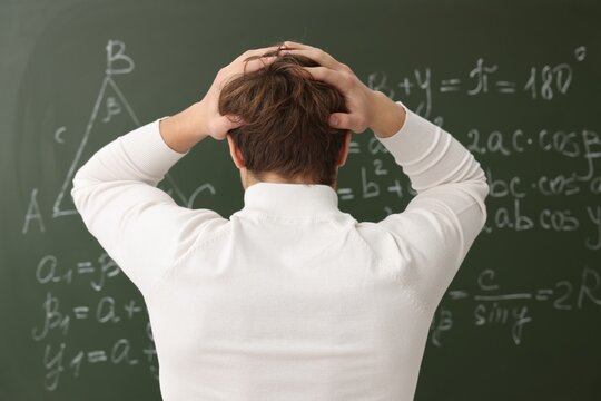 Back to school. Student near chalkboard with math assignment indoors